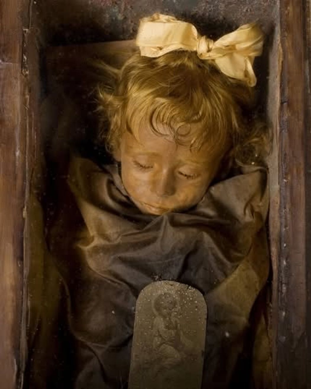 The mummy of Rosalia Lombardo .In the depths of an obscure Sicilian catacomb, there lies a young girl in an open casket. Her name is Rosalia Lombardo and she died at the tragically young age of two due to co