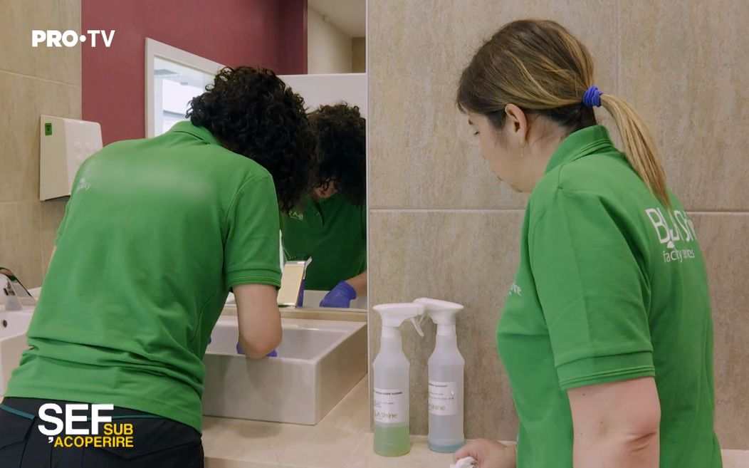 Livia Baba, fondatoarea companiei BLA Shine, face curățenie în baie sub supravegherea angajatei sale, Roxana Bria