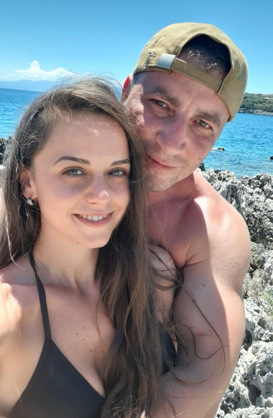 Marian Godină și soția sa zâmbesc în fața camerei de fotografiat, pe o plajă, în vacanța de vară din 2021