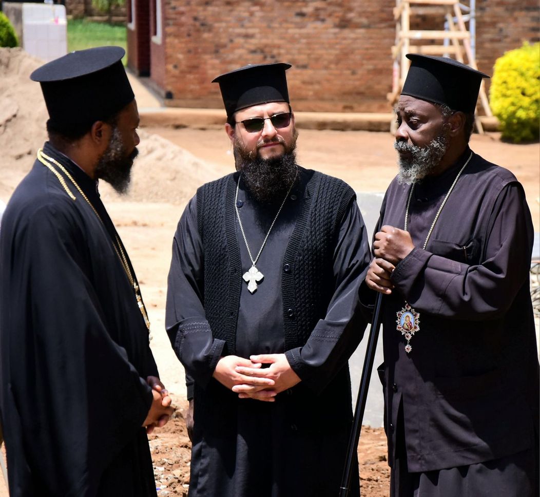 Părintele Nectarie (centru), alături de Părintele Arhimandrit Timoteios, Vicar Patriarhal din Goma, și Părintele Dimitrios prezbiter discută despre sfințirea bisericii ortodoxe din Rwamagana