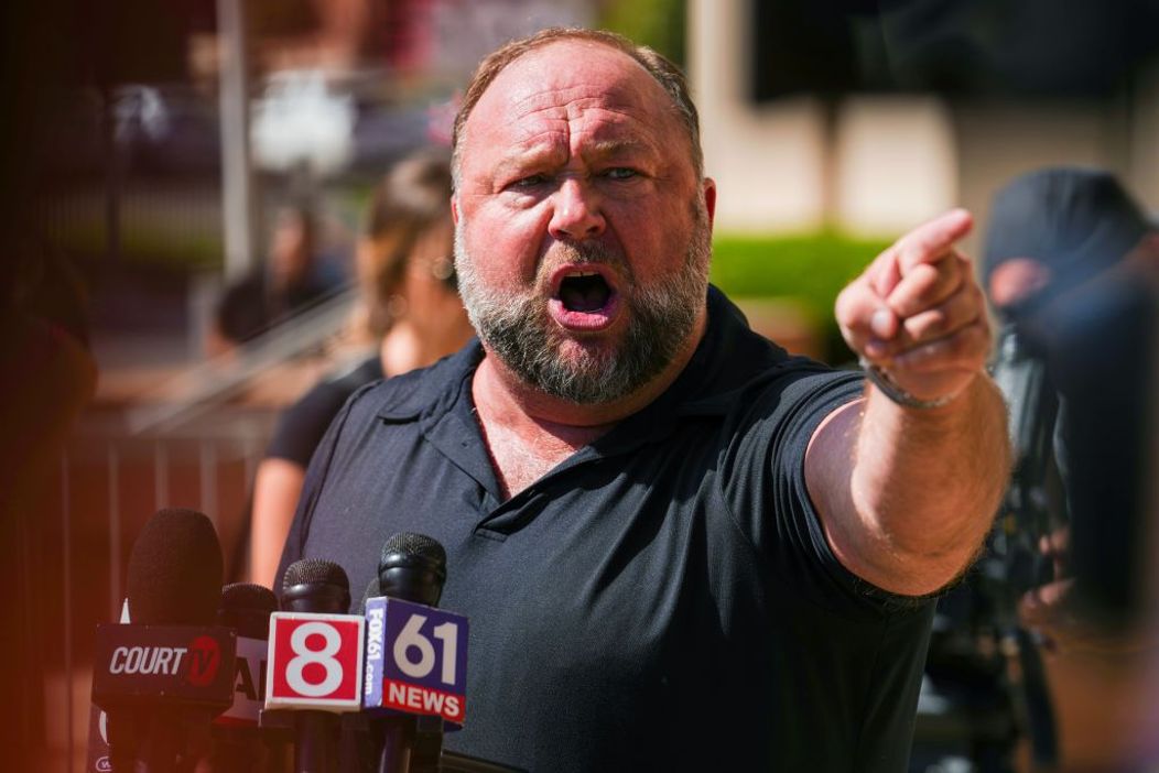 Alex Jones vorbește pe un ton răstit în fața jurnaliștilor din  Waterbury, Connecticut, după decizia Curții Supreme din Waterbury care a hotărât că bărbatul trebuie să achite 49,5 milioane de dolari daune familiei unui băiat de 6 ani ucis în masacrul de l