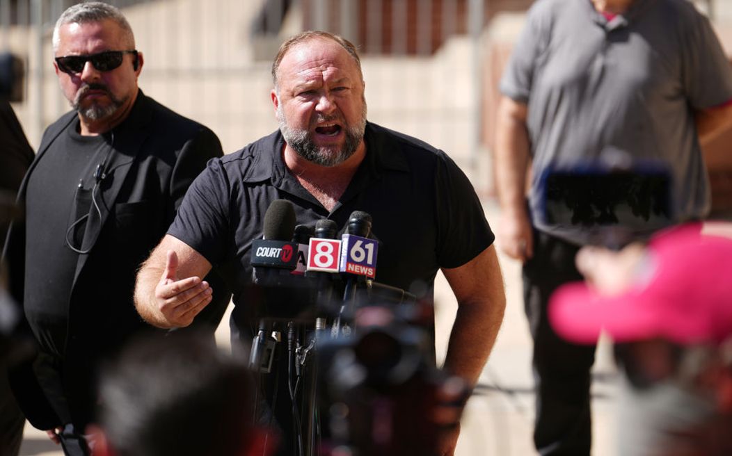 Alex Jones vorbește pe un ton răstit în fața jurnaliștilor din  Waterbury, Connecticut, după decizia Curții Supreme din Waterbury care a hotărât că bărbatul trebuie să achite 49,5 milioane de dolari daune familiei unui băiat de 6 ani ucis în masacrul de l