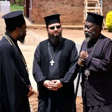 Părintele Nectarie (centru), alături de Părintele Arhimandrit Timoteios, Vicar Patriarhal din Goma, și Părintele Dimitrios prezbiter discută despre sfințirea bisericii ortodoxe din Rwamagana