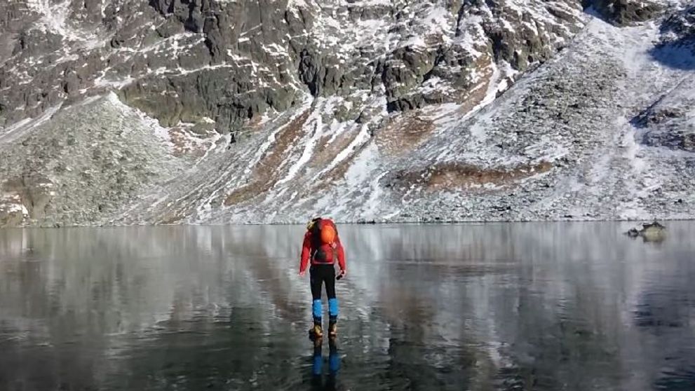 Imaginile care iti taie rasuflarea. Doi alpinisti traverseaza un lac inghetat extrem de limpede - VIDEO